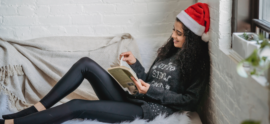 woman in santa hat laying down with book